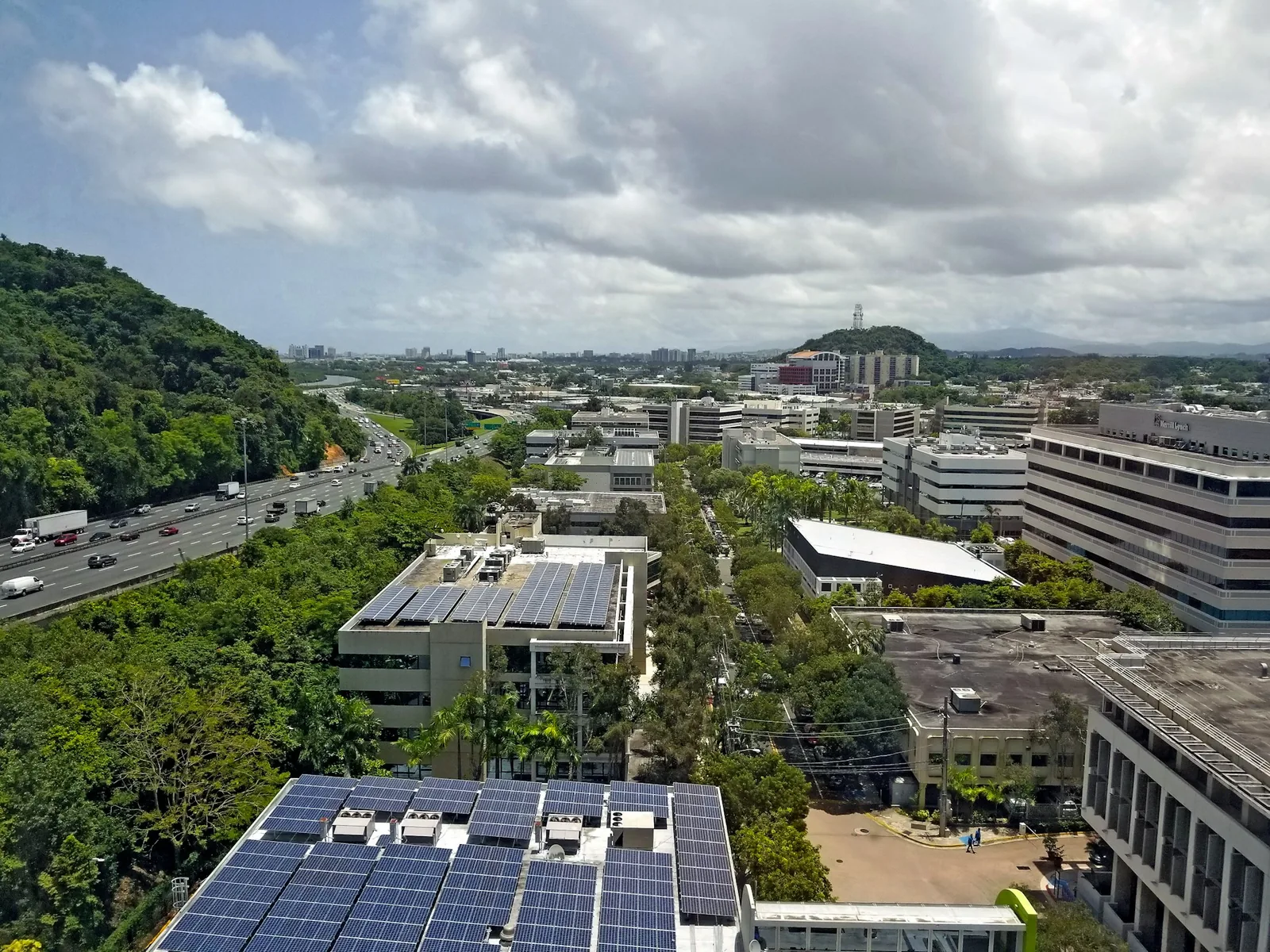 Rooftop solar arrays on office buildings among green hills in Guaynabo, Puerto Rico