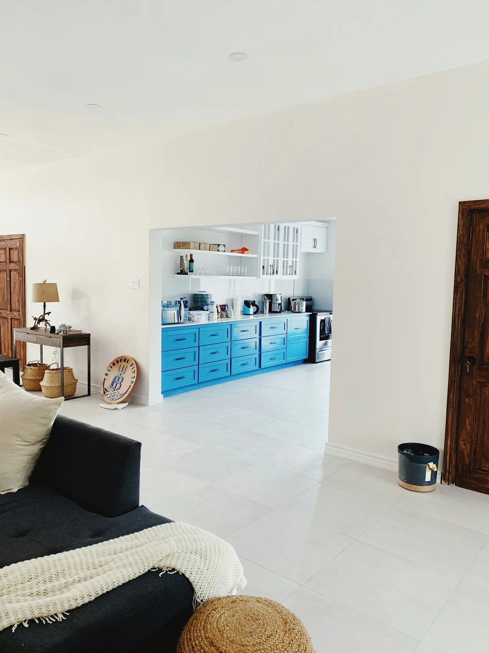 A living area opening into a kitchen with blue cabinetry in Portland, Jamaica