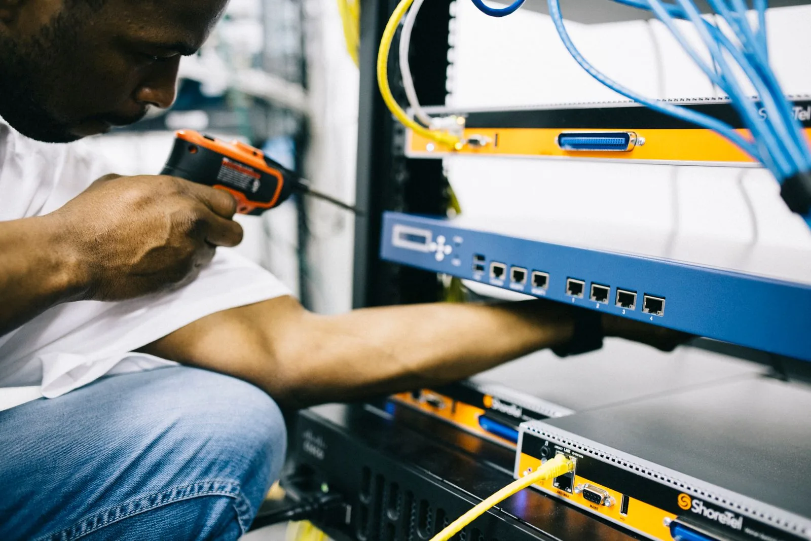 A technician securing networking equipment beside connected cables and ports