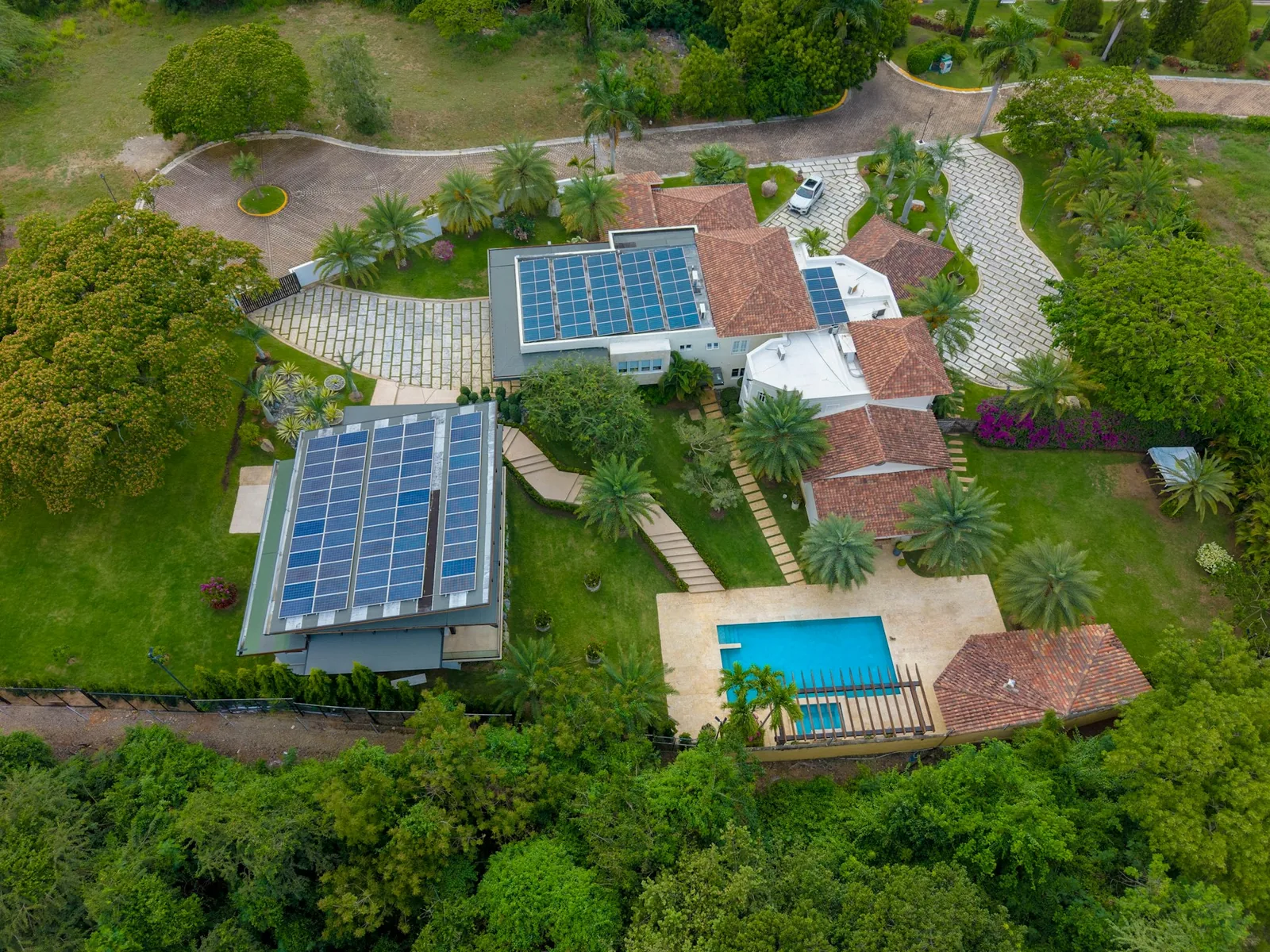 A residence with rooftop solar arrays, tiled roofs and mature tropical trees