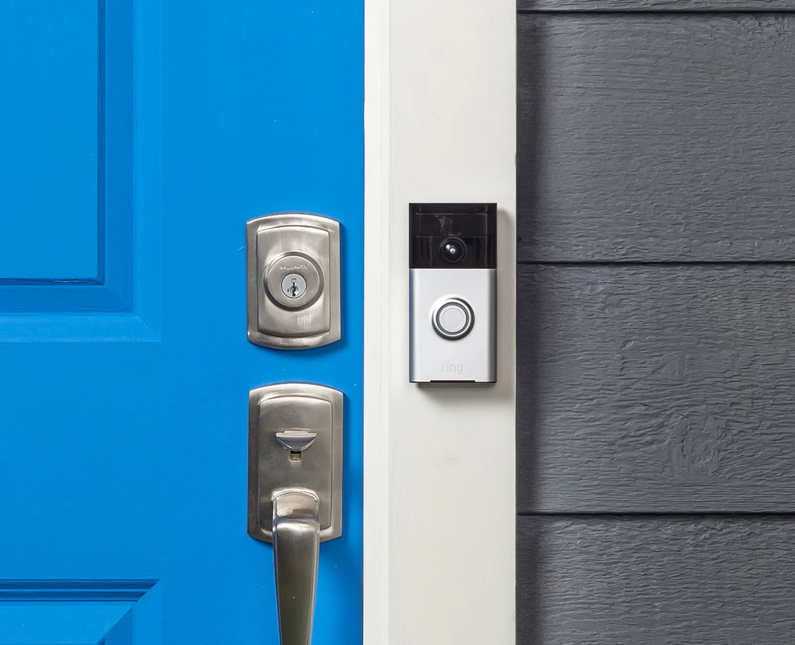 A video doorbell installed beside a blue front door and its lock